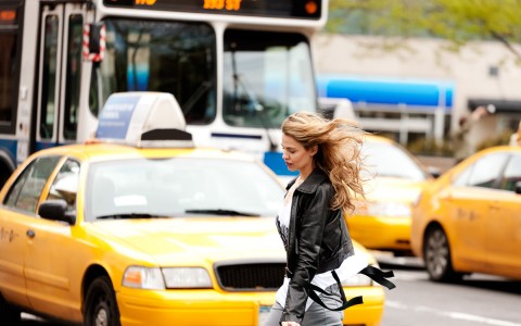 a woman walking in front of a taxi cab